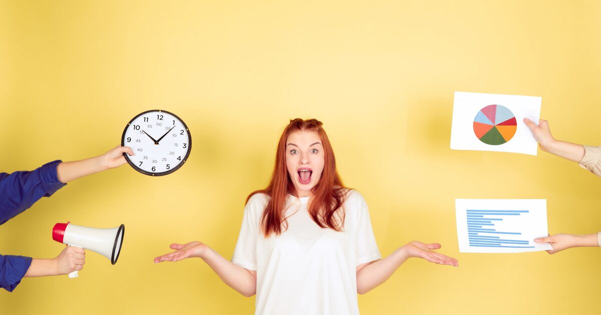 Eine überraschte Frau steht mit ausgebreiteten Armen vor einem gelben Hintergrund. Um sie herum sind Hände, die eine Uhr, ein Megafon, ein Kreisdiagramm und ein Balkendiagramm halten, was Multitasking und Stress symbolisiert.
