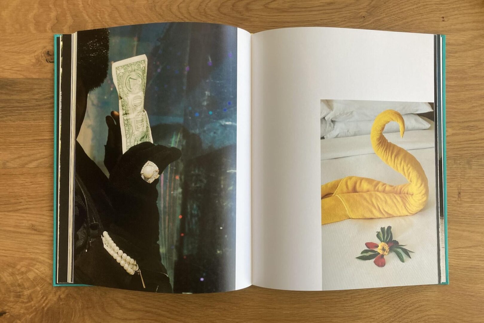 An open book shows a page with a gloved hand holding a dollar bill and a pearl bracelet, and another page with a yellow towel folded into a swirl shape, resembling a horn, on a bed with small decorative items nearby.