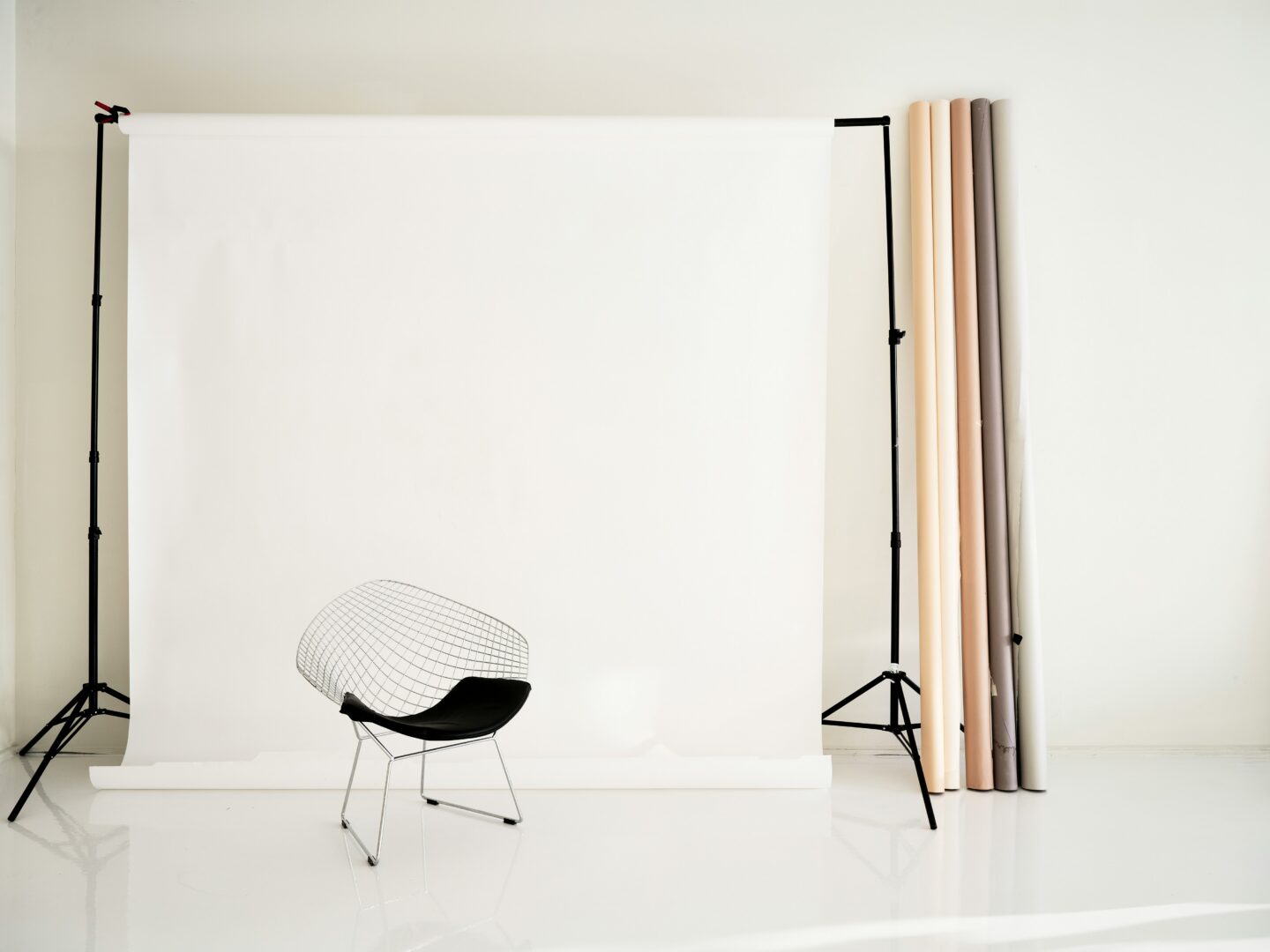 Minimalist photography studio with a white backdrop, chair, and rolled paper backgrounds.